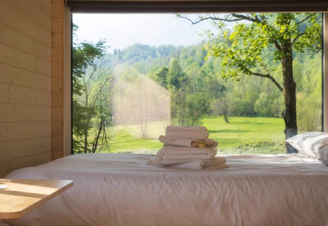 Letto di una casetta Friland con vista sul prato dalla finestra